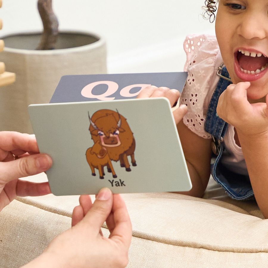 Child learning about a yak with a card held by an adult